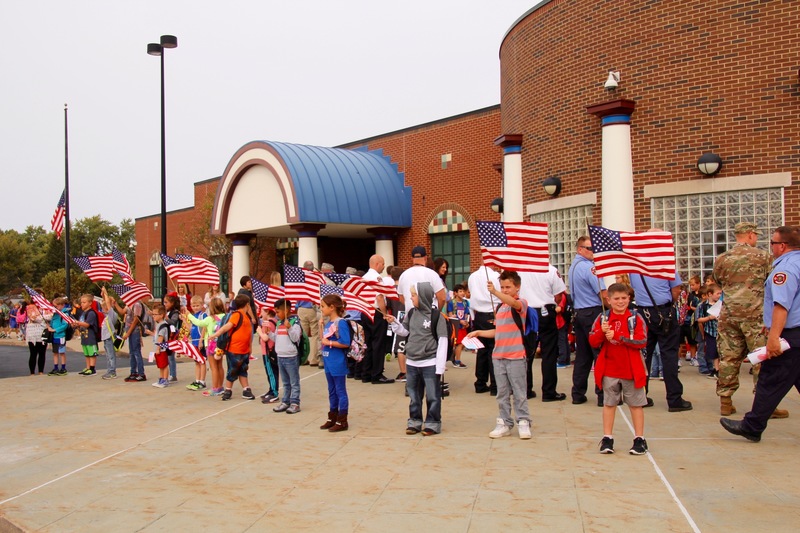 At dismissal, students from each class lined the front sidewalk with flags, while everyone left in silence.