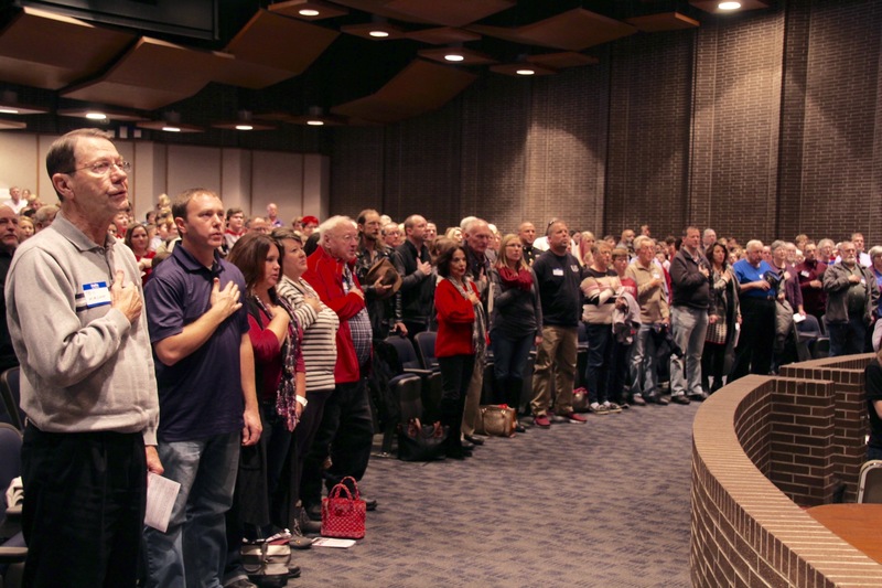 The sound of a full auditorium, reciting the Pledge of Allegiance in one voice.