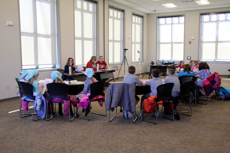 All four teams, their moderator, scorekeeper and timekeeper, and the video cameras that captured the event.