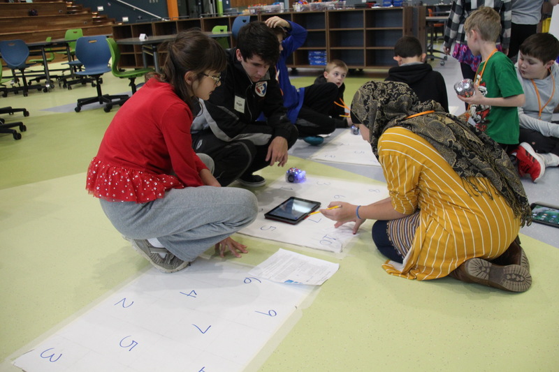 One of our high school interns assisting students with a coding project